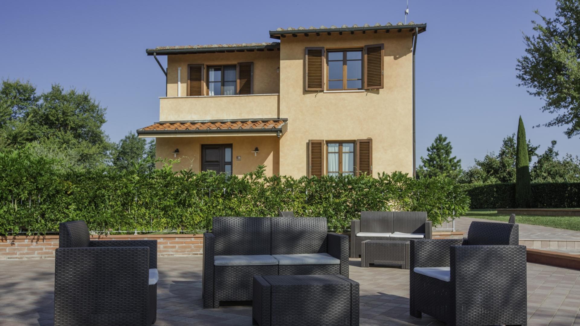 Casa con mobili da giardino e siepe verde.