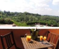 Terrazza con vista collinare, tavolo con succo d'arancia e bottiglia di champagne.