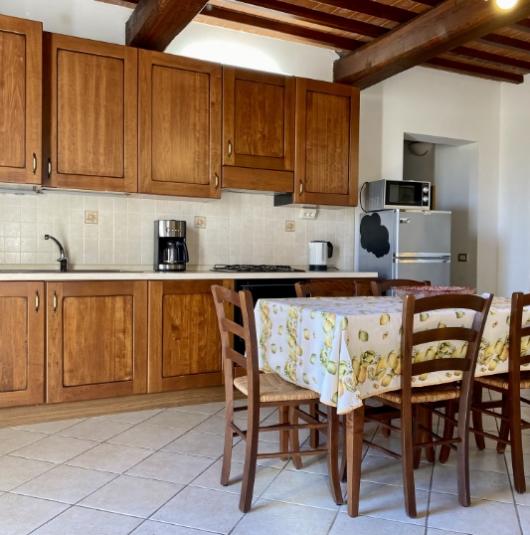 Cucina rustica con mobili in legno, tavolo con tovaglia e sedie in legno.