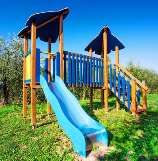 Scivolo blu per bambini in un parco giochi con struttura in legno.