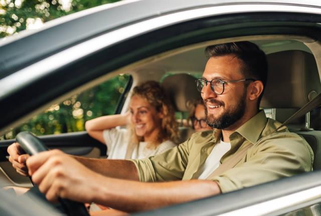 Gruppo di amici sorridenti in auto durante un viaggio su strada.