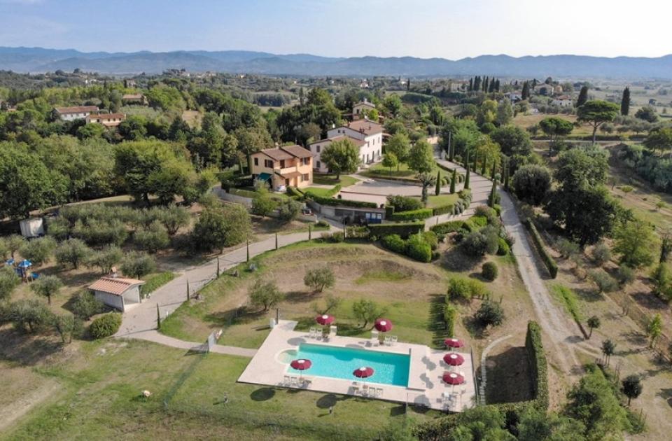 Vista aerea di un complesso con piscina e case in campagna.