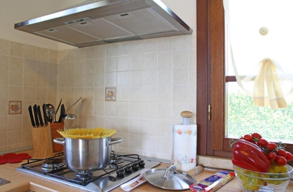 Cucina con pentola di spaghetti, coltelli, verdure e confezione di pasta.