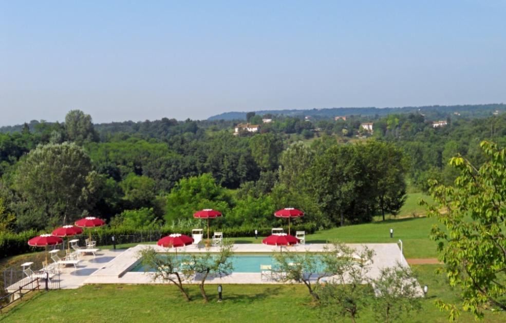 Pool mit roten Sonnenschirmen inmitten von Grün.