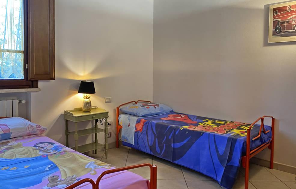 Camera con due letti singoli, lampada e biancheria colorata per bambini.