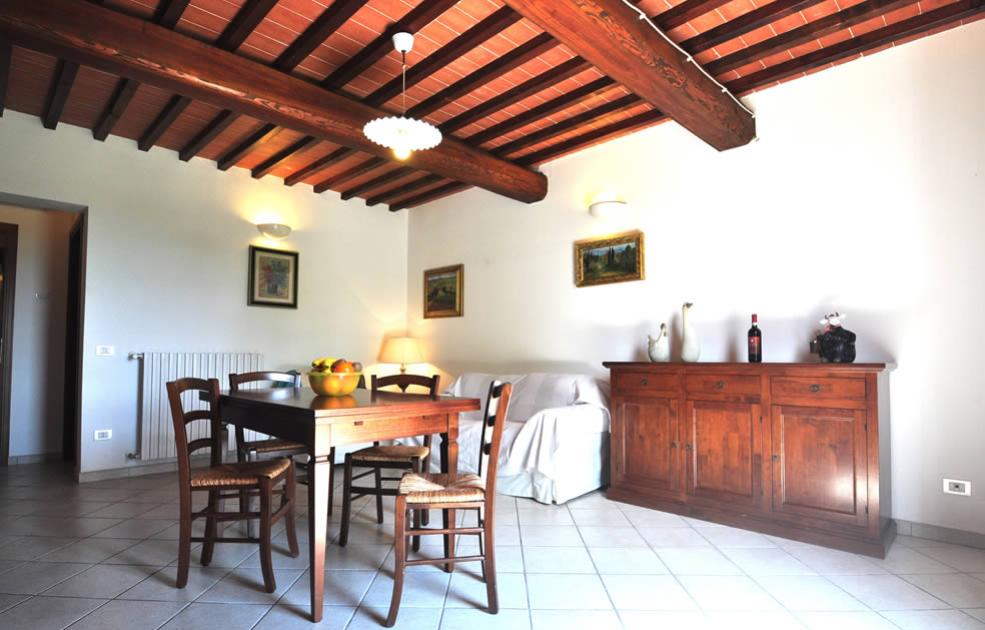 Soggiorno rustico con travi a vista, arredi in legno e tavolo da pranzo.