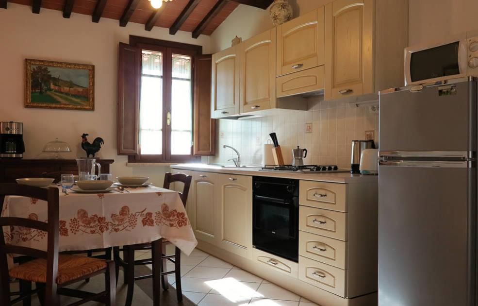 Cucina accogliente con tavolo apparecchiato, mobili in legno chiaro e finestra luminosa.