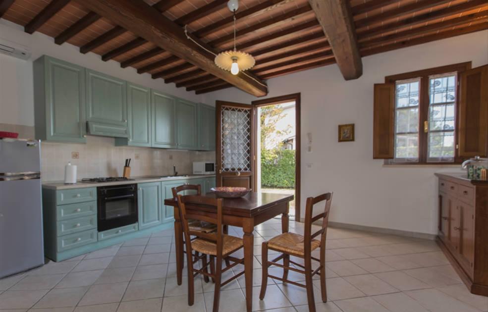Cuisine rustique avec poutres apparentes et meubles verts.