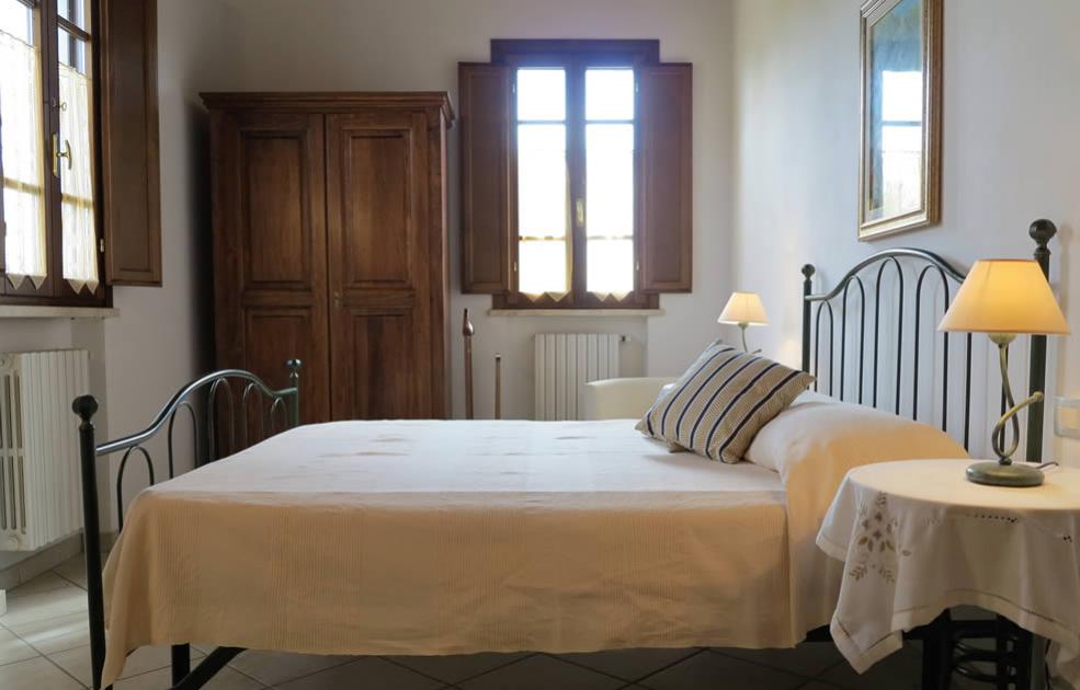 Camera da letto accogliente con letto in ferro battuto e mobili in legno.