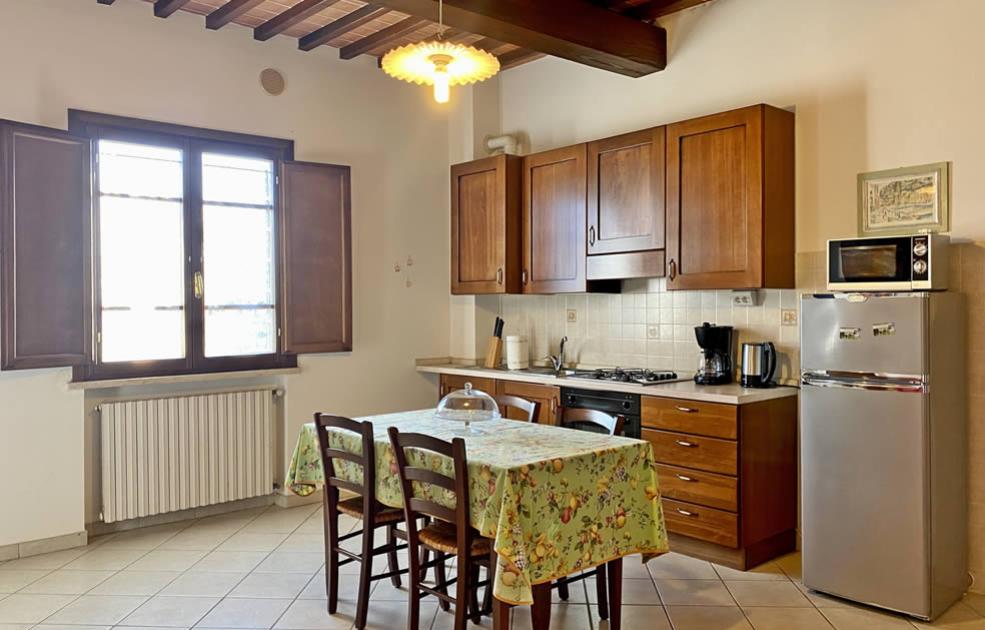 Cucina accogliente con tavolo, mobili in legno, e elettrodomestici moderni.