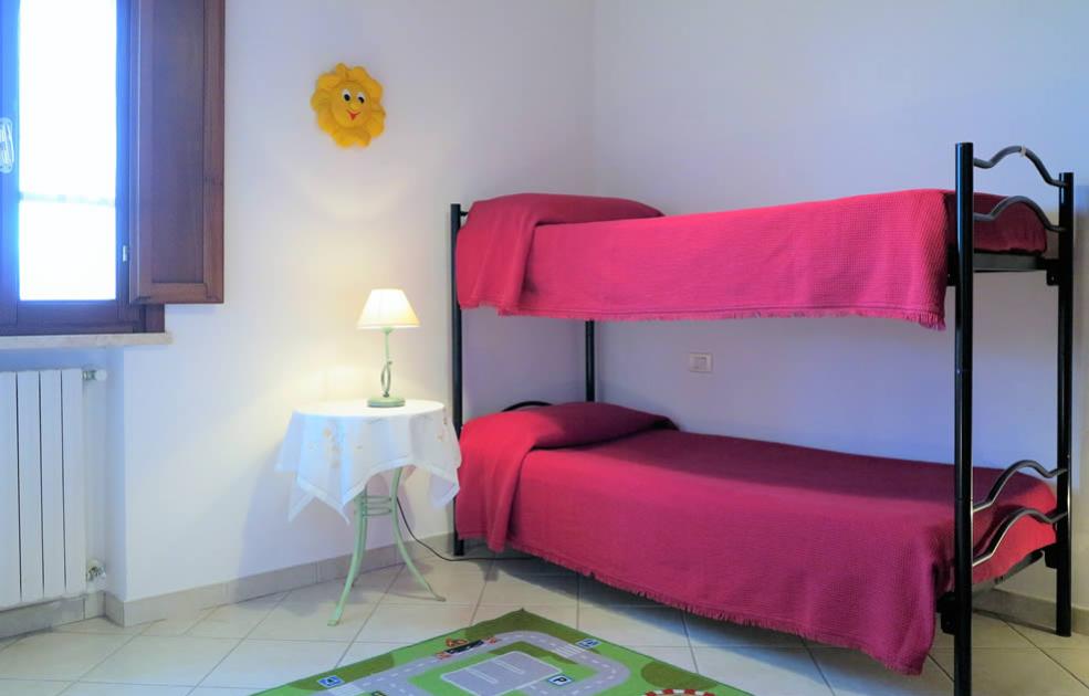 Camera con letto a castello, lampada e tappeto colorato.