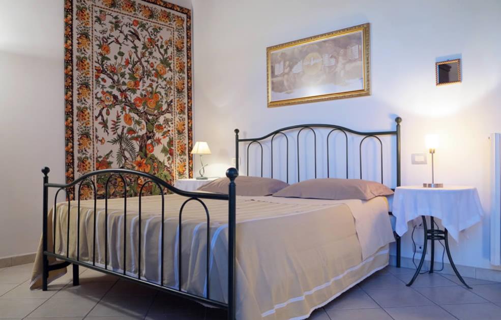 Camera accogliente con letto in ferro battuto e arazzo floreale sulla parete.
