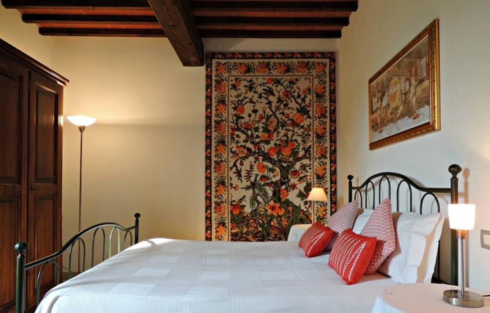 Camera da letto con letto in ferro, arazzo floreale e cuscini decorativi.